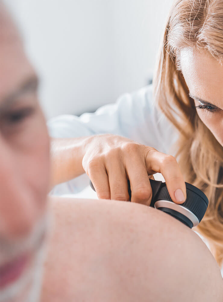 A doctor checking the skin of an older man for skin cancer.